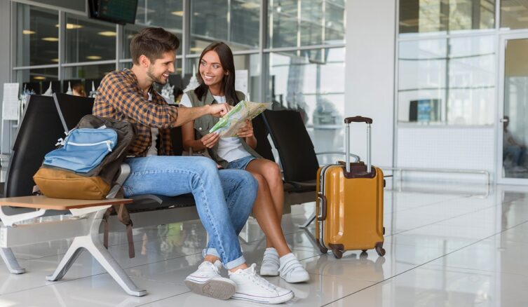 Happy,Young,Couple,Is,Sitting,In,Airport,Near,Suitcase.,They